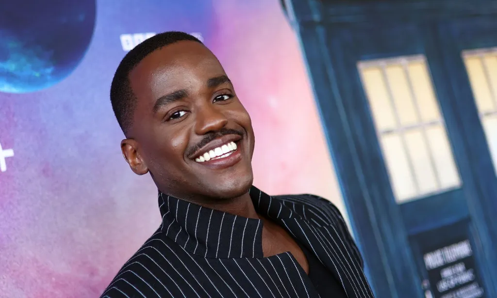 Ncuti Gatwa sonriendo con un traje negro a rayas en el estreno de Doctor Who