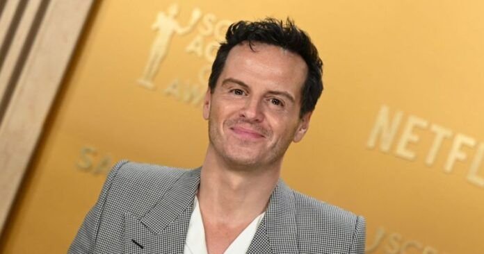 Andrew Scott con traje gris y camisa blanca sonriendo en la alfombra roja de los Premios SAG 2025.